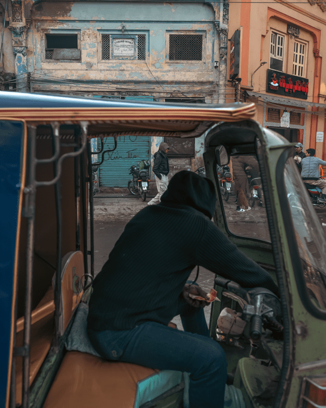 A street photograph showing a parked rickshaw with colours coordinated with those of the wall at the back