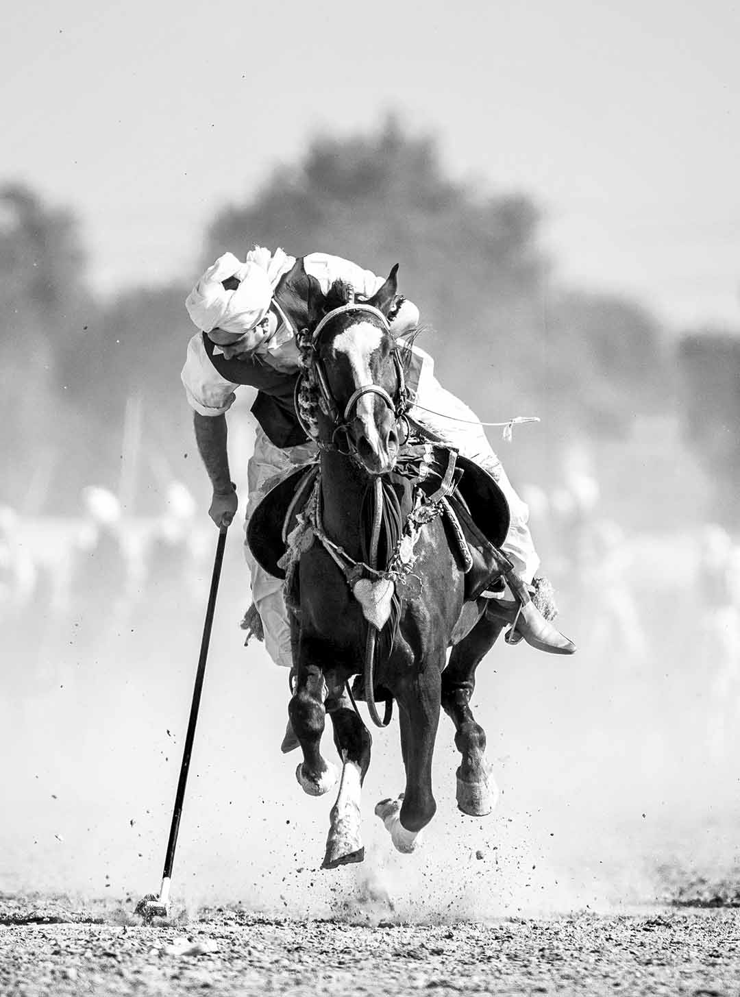 Black and white photograph of a tent pegging rider in rural Punjab, captured mid-gallop in dust. A3 fine art prints of this image is available for order.